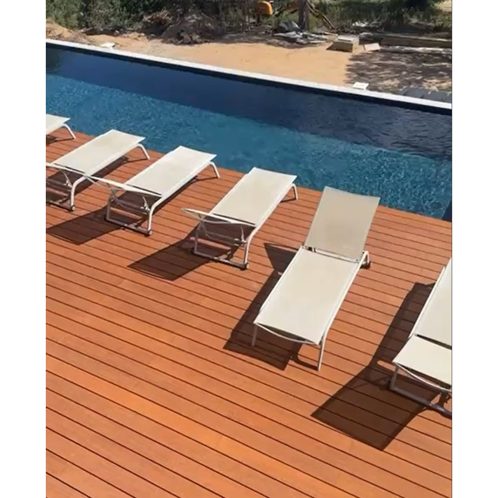 Terrasse bambou avec bains de soleil au bord d'une piscine